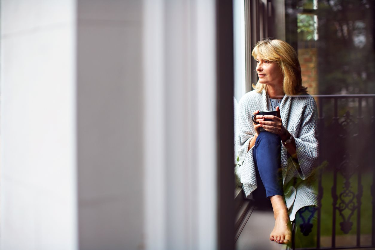 Woman with coffee looking out a window