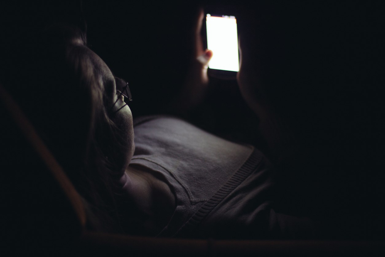 Lying in the dark reading texts on phone